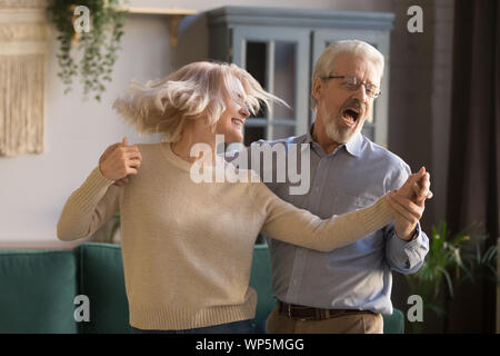 Active happy mature couple have fun dancing at home Stock Photo