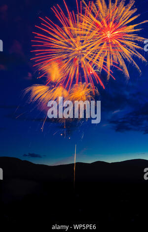 4th of July fireworks over a mountain meadow at dusk, Stowe, Vermont, USA. Stock Photo