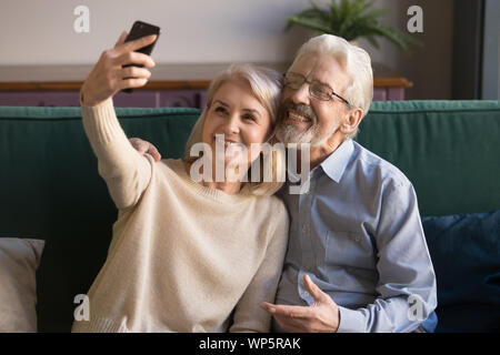 Modern smiling senior couple take selfie on smartphone Stock Photo