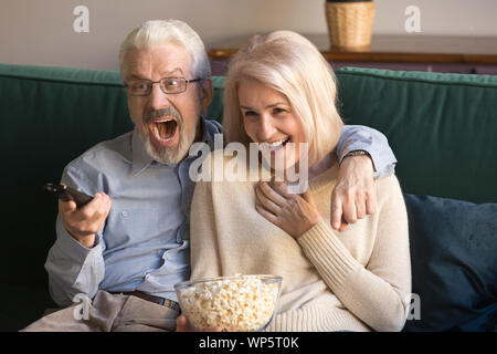Senior family couple sport fans watching football on tv. Stock Photo