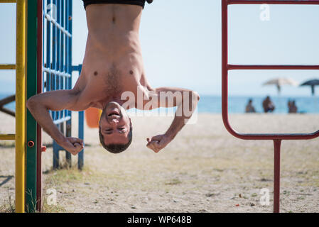 Man hanging upside down at the beach in Greece Stock Photo