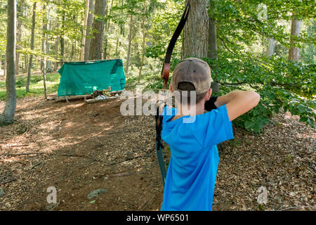 boy with cap and blue shirt shooting bow Stock Photo