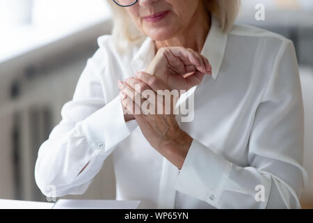 Senior woman worker suffering from wrist spasm or strain Stock Photo