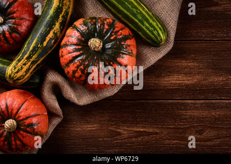 Flat lay Photo Orange pumpkins and green zucchini on sacks of jute. Old wooden table top or background.