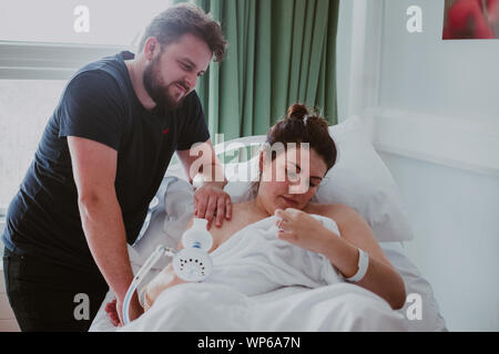 Authentic birth images, new parents looking at their newborn baby in a midwife led unit in the hospital