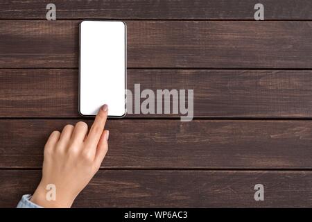 Hand using mobile phone with blank screen on wooden background Stock Photo