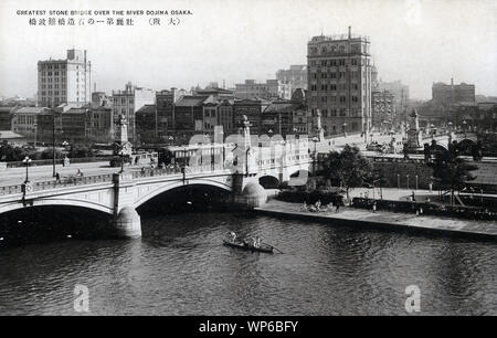 [ 1920s Japan - Naniwabashi Bridge, Osaka ] —   Naniwabashi Bridge spans the Old Yodo River and was completed in 1915.  The bridge was well known for its lampposts and stone statues of lions. It featured impressive stone steps leading to Nakanoshima Island and the waterfront park which was under construction at the time the bridge was built.  It still stands and is one of the oldest Western style bridges in Japan.  20th century vintage postcard. Stock Photo