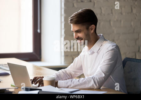 Smiling businessman using laptop, working online or writing email Stock Photo
