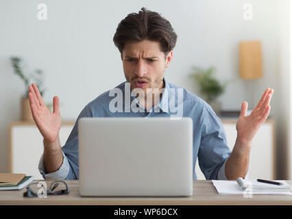 Shocked Man Looking At Laptop Having Problem Working At Home Stock Photo
