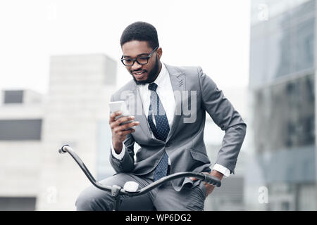 Handsome businessman using smartphone, riding on bicycle Stock Photo