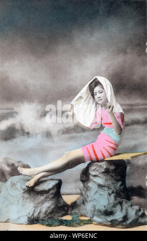 [ 1910s Japan - Japanese Woman in Bathing Suit ] —   A studio photo of a young woman with traditional hair styles posing in a bathing suit. Models for these kind of photos were almost always geisha.  20th century vintage postcard. Stock Photo