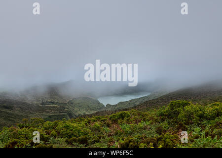 Landscape of low clouds and bad weather over Lagoa Funda das Lajes caldera volcanic crater lake at Ilha das Flores island in the Azores, Portugal Stock Photo