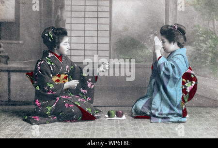 [ 1910s Japan - Japanese Women in Kimono ] —   Two young women in kimono and traditional hairstyles appear to be playing janken (rock-paper-scissors).  20th century vintage postcard. Stock Photo