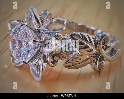 WHITE DIAMOND RING SILVER ALUMINUM STEEL BODY CLOSEUP WITH FLOWER AND LEAVES DESIGN MACRO IMAGE CRYSTAL SHINE ON A TABLE Stock Photo