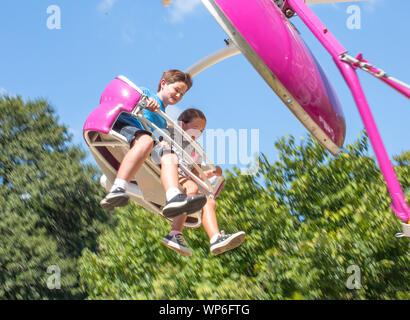 MATTHEWS, NC (USA) - August 31, 2019: Two children enjoy a carnival ride at the annual 'Matthews Alive' community festival. Stock Photo