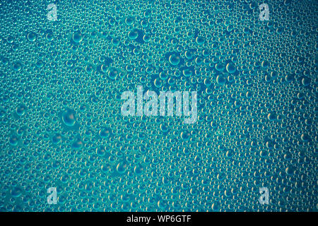 Water drops on aquamarine surface. Dark green abstract background of bright soap bubbles. Blue texture of shiny glass. Drops pattern. Modern design. T Stock Photo