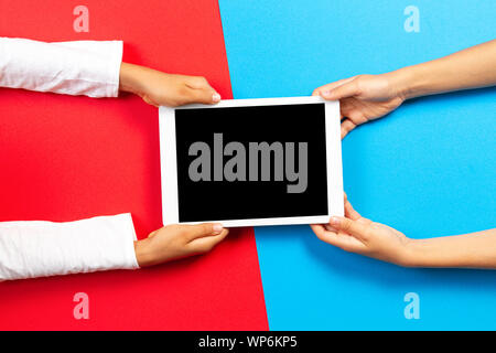Kids holding tablet computer over red and light blue background Stock Photo