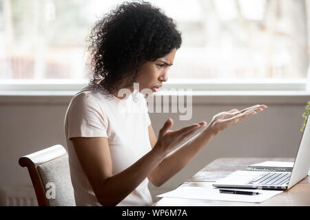 Mad biracial woman frustrated by computer operational problems Stock Photo