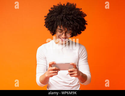 Cheerful young man watching video on cellphone Stock Photo