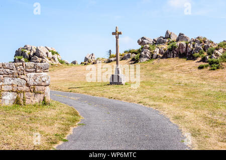 Granite calvary in Brittany, France, on the side of a small country road in front of a granite outcrop on a sunny summer day. Stock Photo