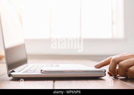 Closeup of female using smartphone that lying on laptop Stock Photo