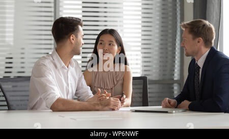 Smiling chinese young woman holding husbands hand, discussing bank loan. Stock Photo