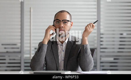 Concentrated african american male ceo negotiating on smartphone with client. Stock Photo
