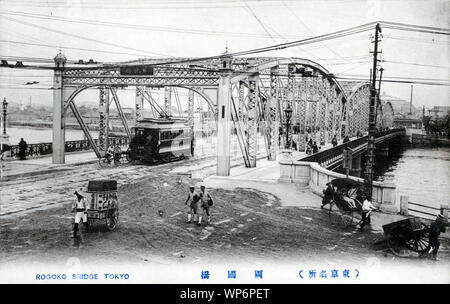 [ 1910s Japan - Japanese Streetcar on a Western-Style Bridge in Tokyo ] —   A streetcar crosses the 1904 Ryogokubashi bridge spanning the Sumidagawa River in Tokyo.  On August 10th, 1897 (Meiji 30) a 10 meter stretch of guardrail of the last wooden wooden Ryogokubashi bridge collapsed when a crowd was watching the famous Sumida river fireworks. More than ten people died.  As a result, a steel bridge was constructed 20 meters downstream from the wooden bridge in 1904 (Meiji 37). It was 164.5 meters long and 24.5 meters wide.  20th century vintage postcard. Stock Photo