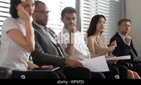 Worried stressed mixed race people applicants sitting in queue. Stock Photo
