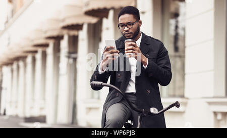 Happy businessman using mobile phone, drinking coffee outdoors Stock Photo