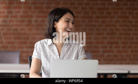 Cheerful asian business woman talking with somebody aside. Stock Photo