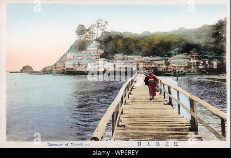 [ 1910s Japan - Enoshima Bridge ] —   A woman in kimono walks on the wooden bridge to the island of Enoshima in Kanagawa Prefecture, Japan. The bridge was approximately 600 meters long.  Enoshima's first bridge was built in 1897 (Meiji 30). In 1949, a new concrete bridge was built. This was changed to a ferro-concrete bridge in 1958. In 1964, the island was linked by a massive concrete bridge to accommodate modern traffic, accompanied by lots of development on the island itself.  20th century vintage postcard. Stock Photo