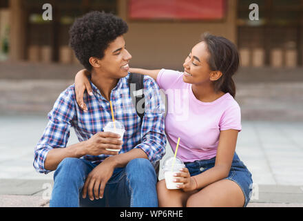 Smiling african teenagers drinking takeaway cocktails, having fun outdoors Stock Photo