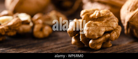 Walnuts. Kernels and whole nuts on wooden rustic table closeup, banner Stock Photo