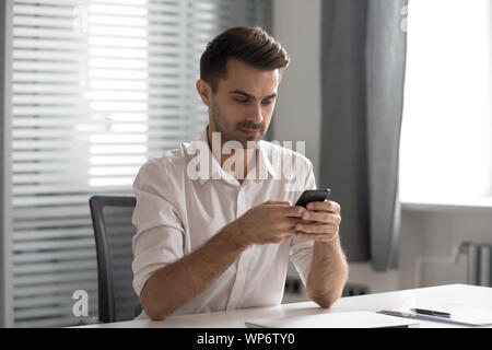 Serious young executive manager using internal company messenger application. Stock Photo