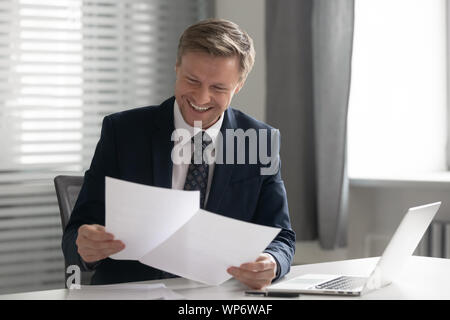 Happy male manager holding financial document with good indicators. Stock Photo