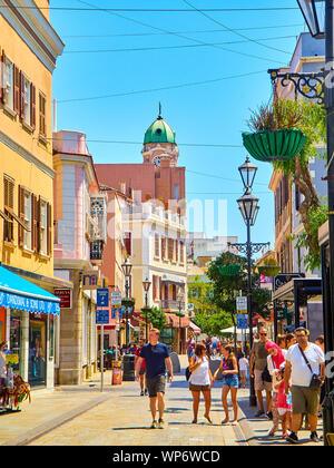 Tourists walking on Main Street at sunny day, with the Belfry of Saint Mary the Crowned Cathedral in the background. Gibraltar. UK. Stock Photo