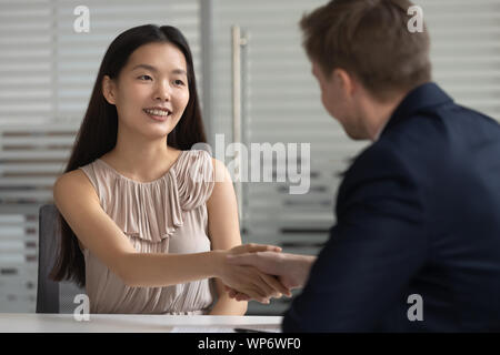 Smiling happy asian young professional shaking hands with hr manager. Stock Photo
