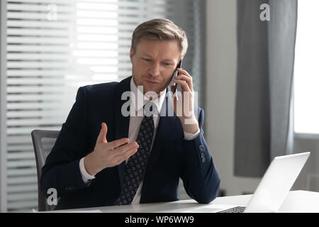 Focused confident businessman holding business call with corporate client. Stock Photo