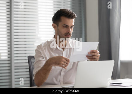 Concentrated young executive manager looking through financial documentation. Stock Photo