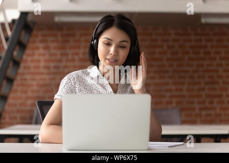 Young asian support service female worker in earphones consulting client. Stock Photo
