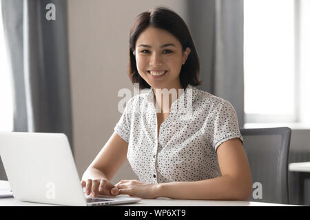 Happy motivated asian female employee working with computer portrait. Stock Photo
