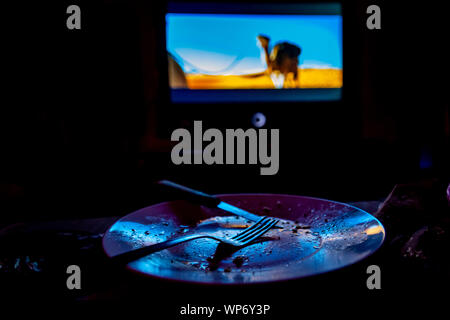 empty plate in front of tv-eating while watching film in tv project Stock Photo