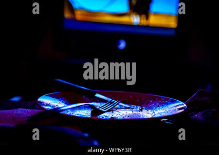 empty plate in front of tv-eating while watching film in tv project Stock Photo