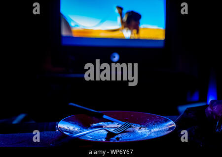 empty plate in front of tv-eating while watching film in tv project Stock Photo