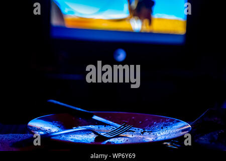 empty plate in front of tv-eating while watching film in tv project Stock Photo