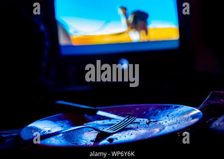 empty plate in front of tv-eating while watching film in tv project Stock Photo