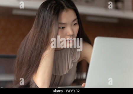Stressed young asian female employee stuck with difficult task. Stock Photo