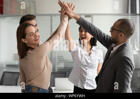 Excited young female team leader giving high five to colleagues. Stock Photo