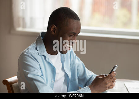 Overjoyed biracial man feel euphoric texting on smartphone Stock Photo
